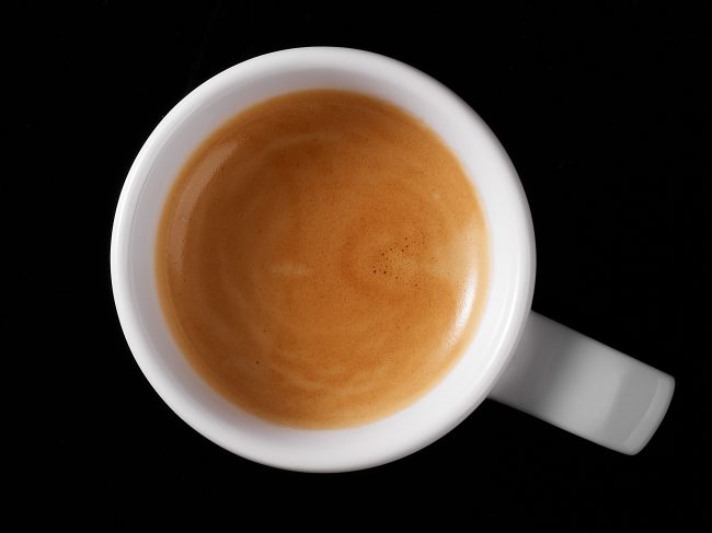Kaffee oder Tee in Tasse in Vogelperspektive fotografiert lecker crema frisch eingeschenkt