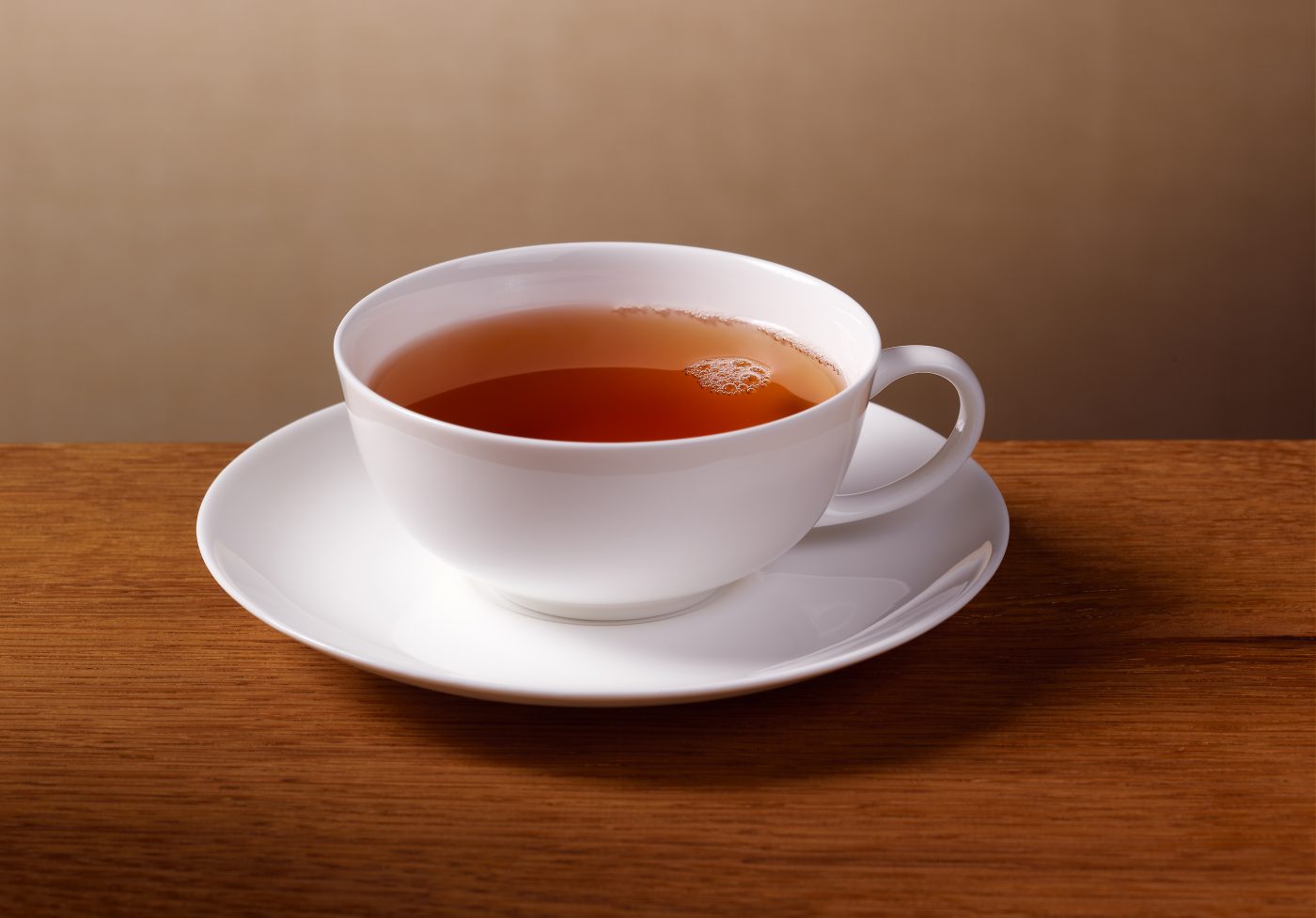 klassische Teetasse mit Tee gefüllt auf Eichen Untergrund goldenem Hintergrund Tee oder Kaffee