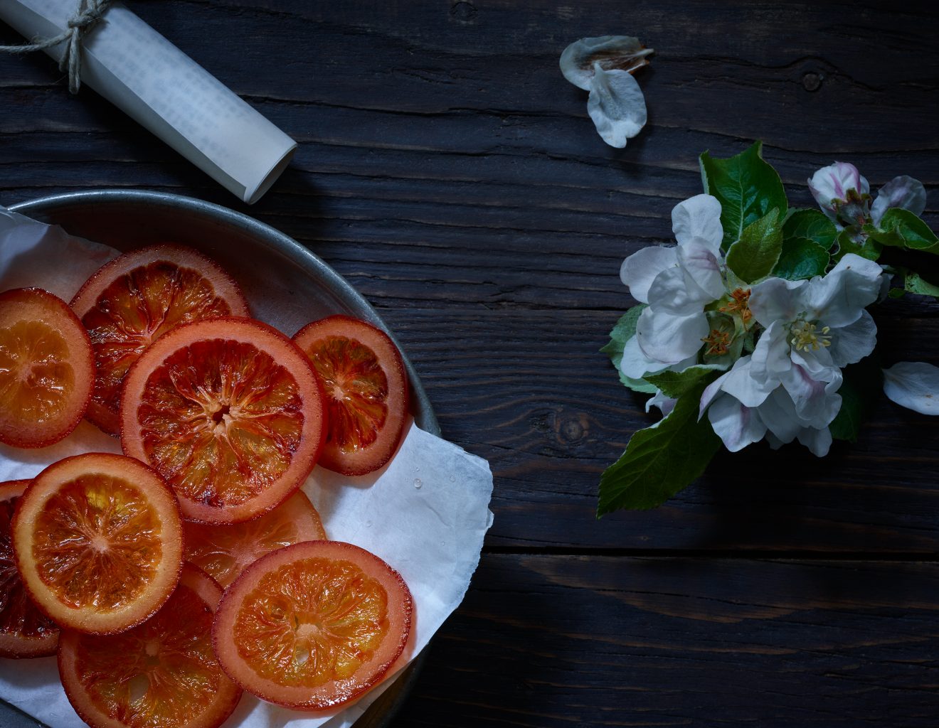 desserts kandiert Orangen Blutorangen auf Schale daneben Papierrolle mit Liebesbrief und schöne Apfelblüte Untergrund aus Holz