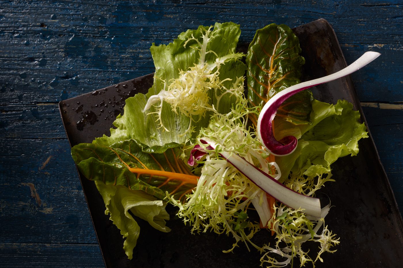Fast food fotografie verschiedene Salate liegen in der Zubereitung auf einem blauen gebrauchten holzbrett und auf holzbrettchen