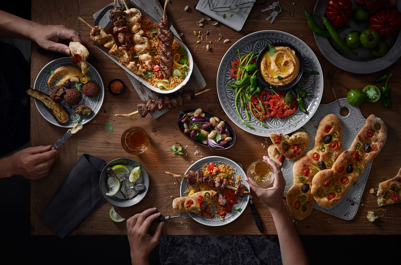 food photography of a big wooden table with allot of dishes mediterranian food hummus meat sauces wine diner