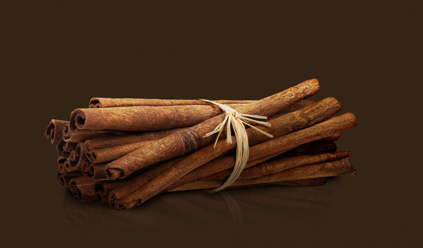 Kaffee mehrere Zimtstangen umwickelt mit Garn Freisteller vor braunem Hintergrund