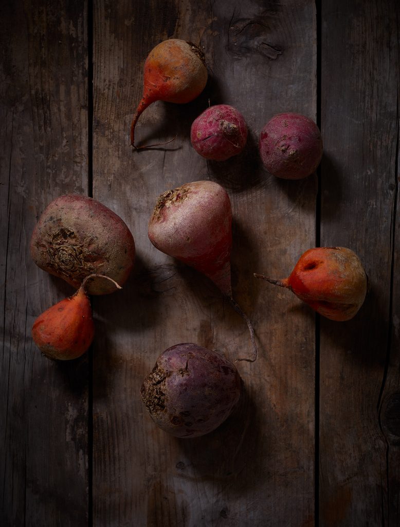 eight beetroot in different colors on washed-out wood underground