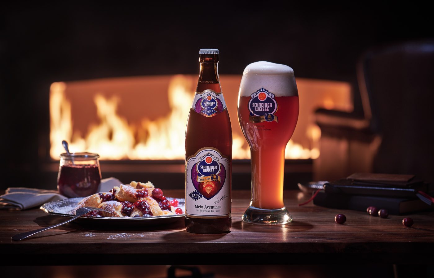 dark wheat beer bottle and filled glas on a wooden table with kaiserschmarrn fireplace as backdrop leather armchair