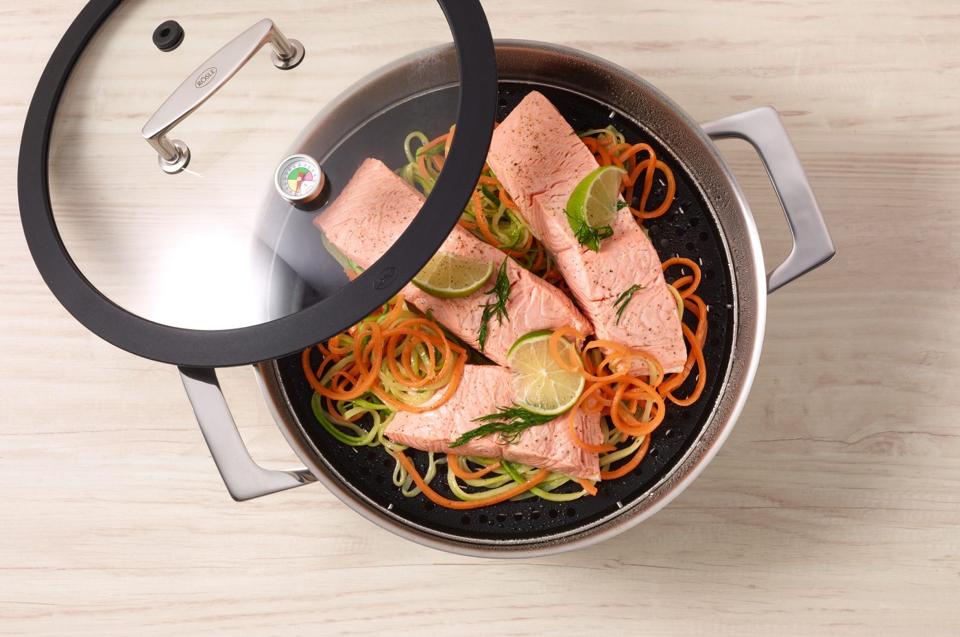 food-verpackungen aromadampfgarer mit lachs lauch gemüsejulienne glesdeckel des topfes liegt mit tautropfen halb auf dem edelstahltopf foodfotos