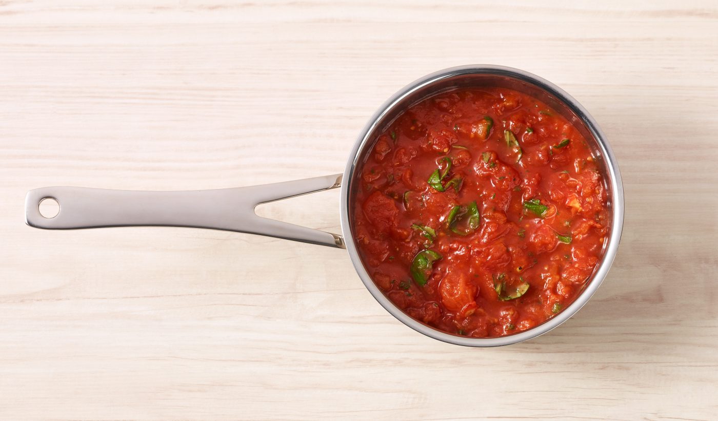 Food-Verpackungen stielkasserolle mit tomatensauce kräutern auf holz