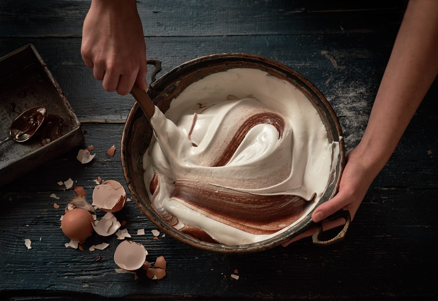 Eischnee wird mit Händen und Kochlöffel unter flüssige Schokolade hehoben, Daraus werden im Ofen Schokoladen Meringue gebacken.