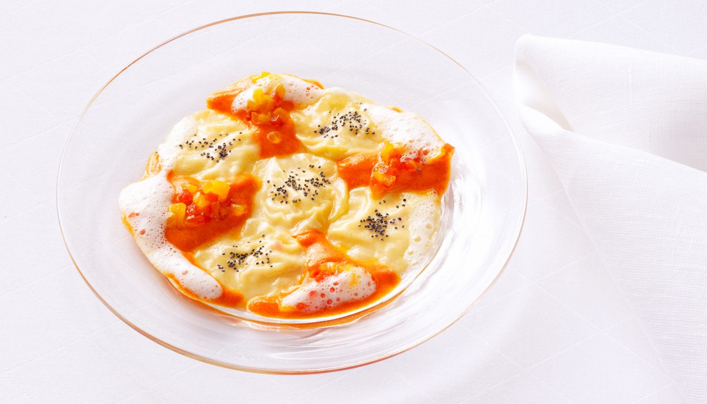 Verpackungsaufnahmen von einem Glasteller mit Ravioli mit Kürbissosse. Weisses Set