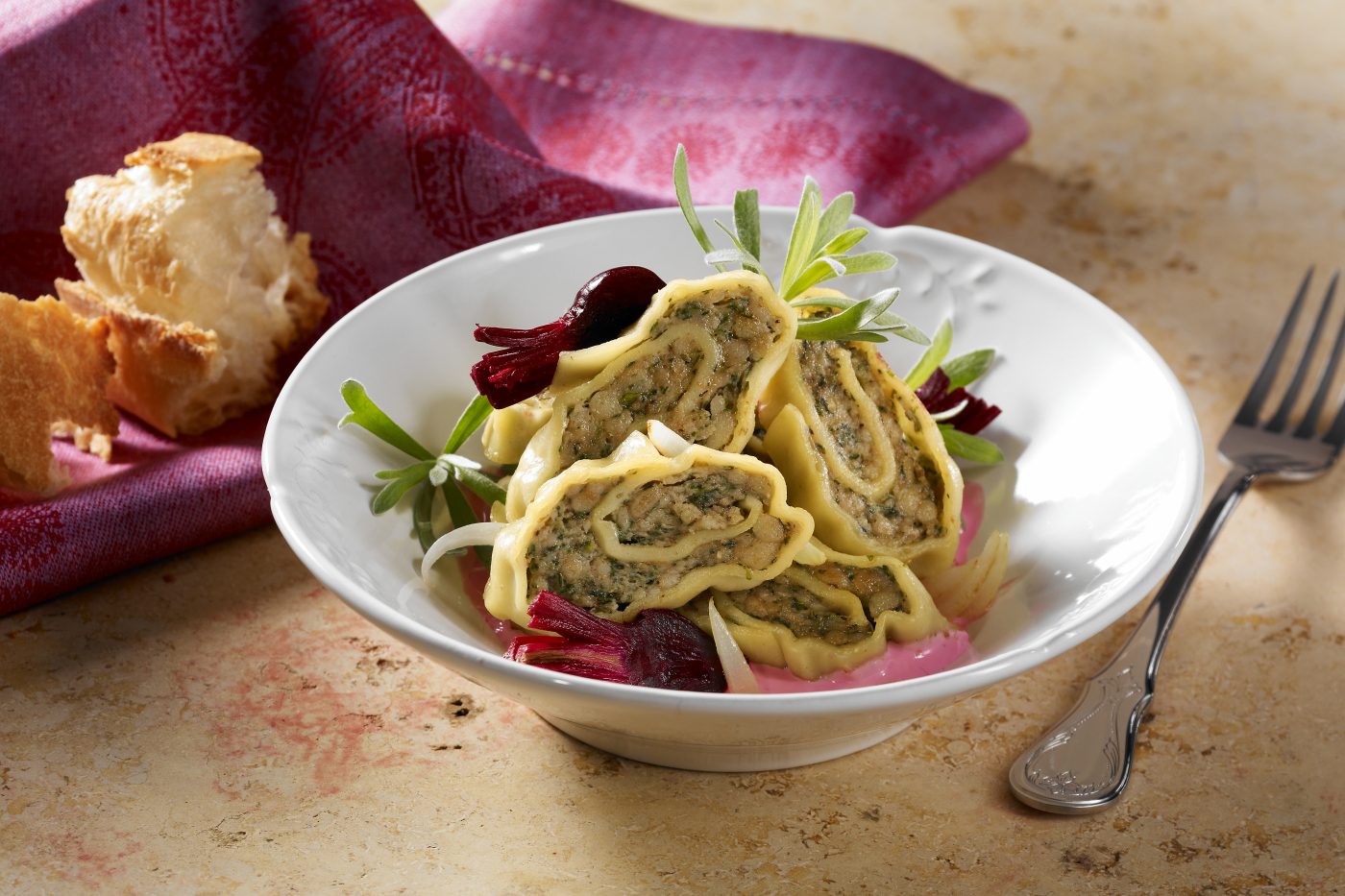 Packaging für Bürger Kalbsfleischtaschen. Aufgeschnittene Kalbsfleischtaschen sind als Salat in einer Schale mit roter Bete angerichtet. Der Untergrund ist ein schöner Steinuntergrund