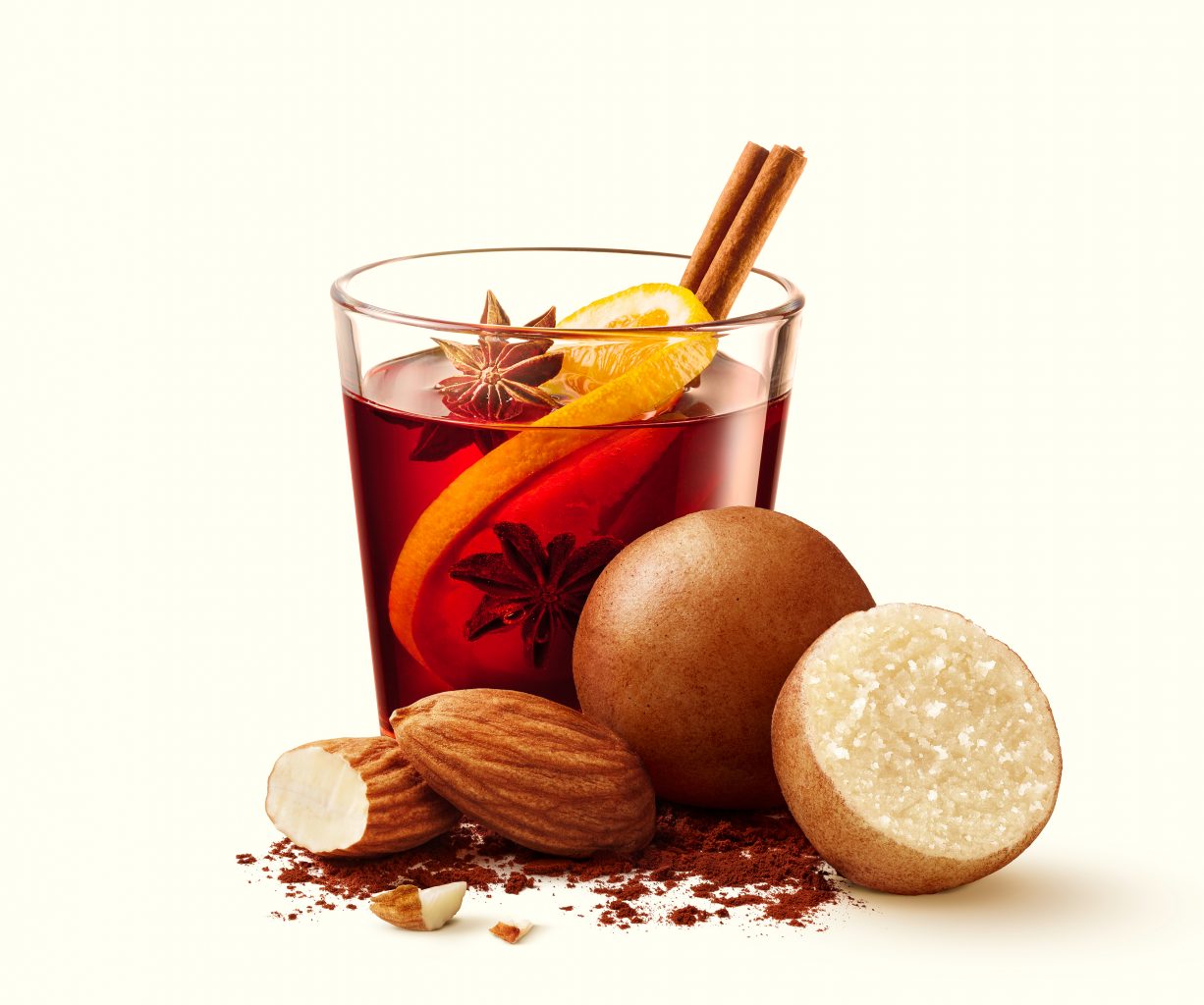 confectionery tea with a cinnamon stick, a whole marzipan ball and a half marzipan ball cut in half lie in front of it. packaging photography