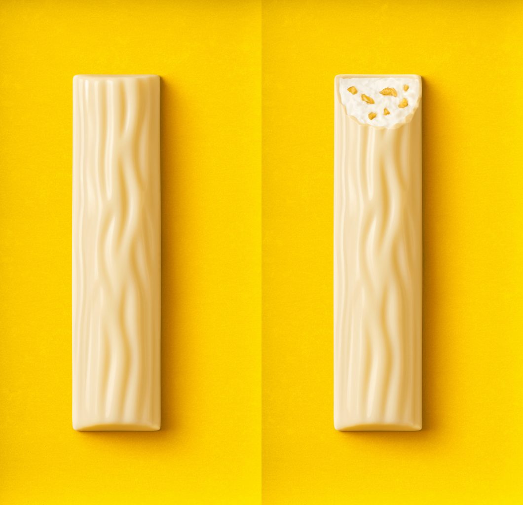 Packaging-Relaunch für die Yoguretten Verpackung. ein angebissener weisser Schokoladenriegel und ein unangebissener weisser Schokoladenriegel Passionsfrucht liegen auf einem gelben Untergrund