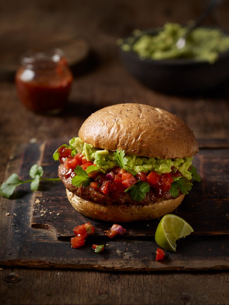 freshly prepared Burger with salad in the background.