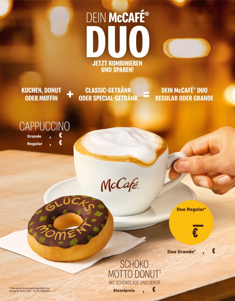 McCafe Cappuccino and Donut are standing on a tray. A womans hand holds the cup
