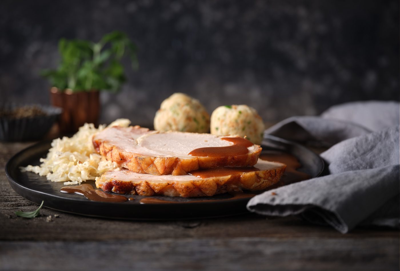 Photo for menuboard with roast pork and dumplings. The dark plate stands in a setting of weathered wood